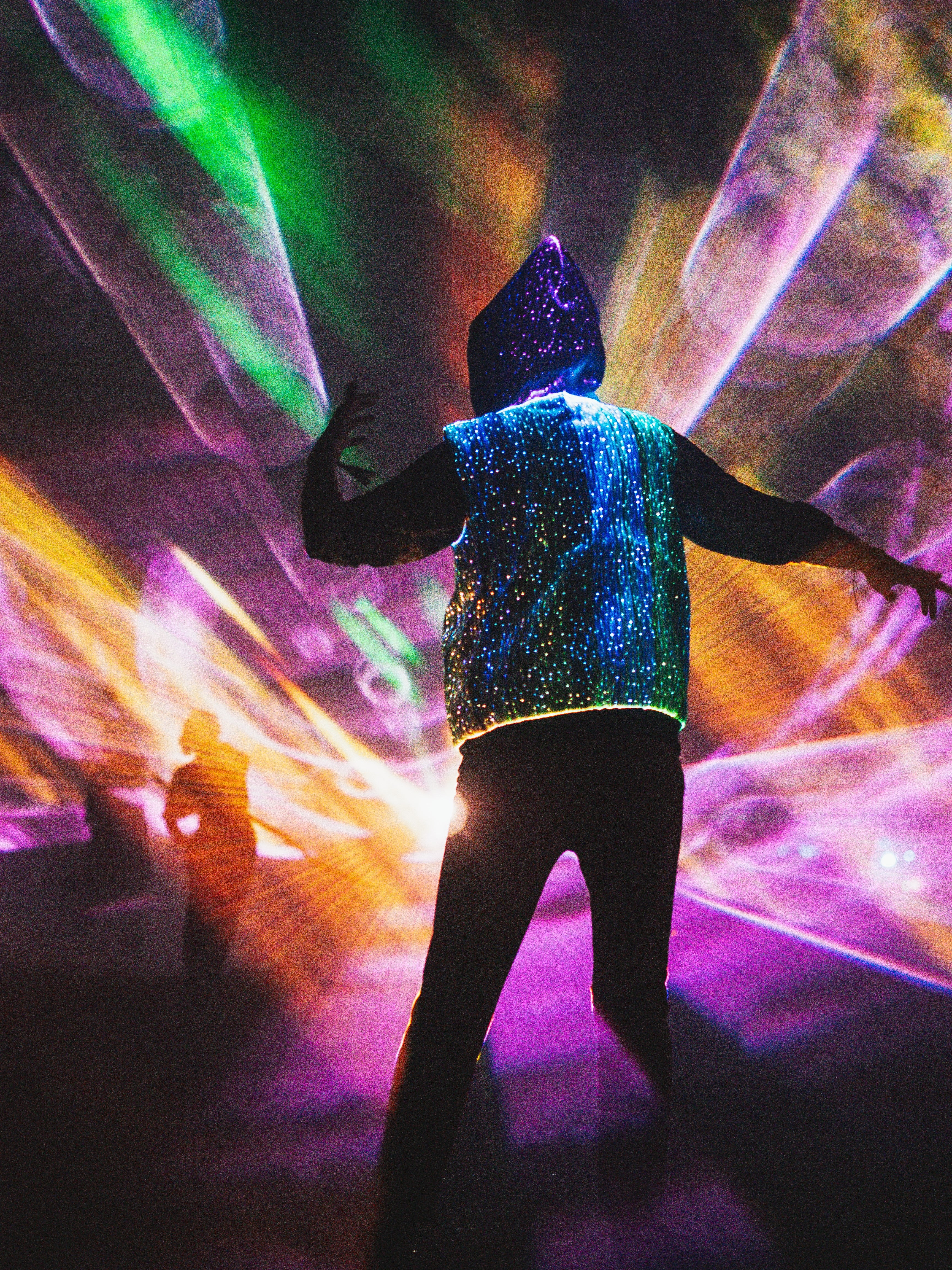 animated man wearing the NEBULITE vest on a festival, with lasers in the background